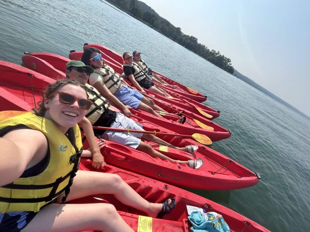 Enjoying a summer day of kayaking on the water at Boyce Thompson Institute, surrounded by nature and clear blue skies, perfect for outdoor team-building and scientific research activities.