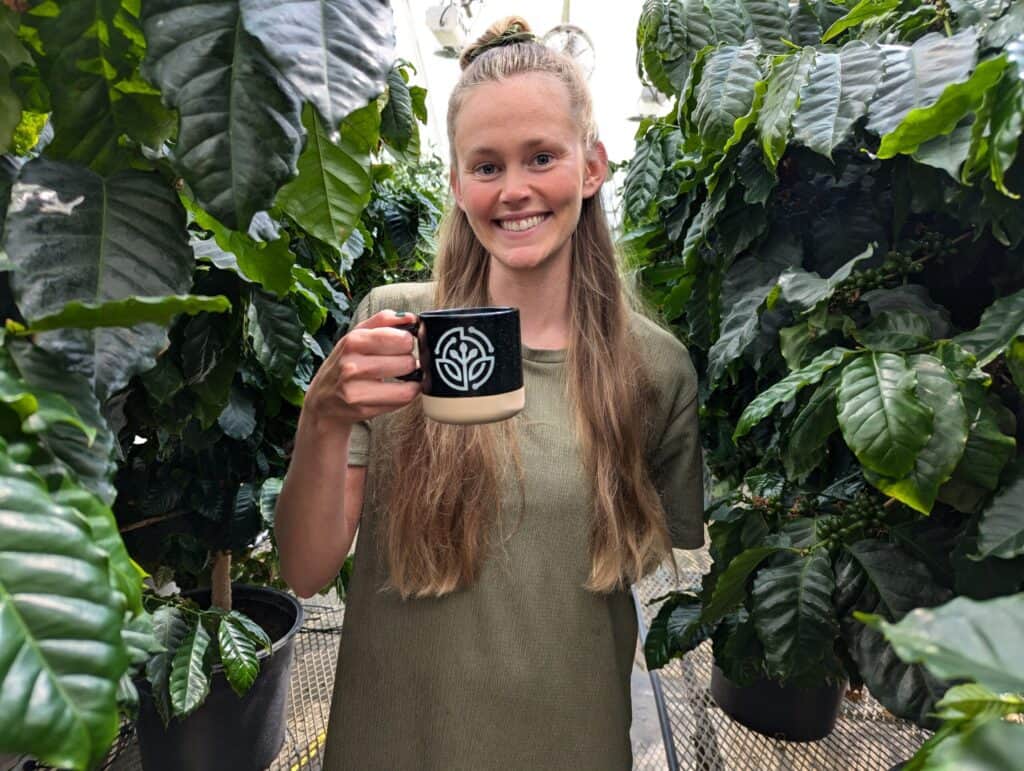 Coffee plant researcher at Boyce Thompson Institute, exploring plant science, sustainable agriculture, and coffee crop innovation in a greenhouse setting.