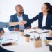 Diverse business team shaking hands at a meeting, representing collaboration and partnership in a professional environment, with focus on teamwork and corporate networking.
